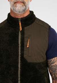Fleece-foringet grøn vest med en mørkebrun yderside, lynlåslukning, orange detaljer og logo. Har to frontlommer og en høj krave.