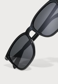 Black sunglasses with a rectangular frame, dark lenses, smooth plastic material, and a subtle shine on the sides. No visible logos or patterns.