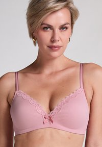 Hellrosa geripptes BH mit Spitze und einer zentralen Schleife. Dünne verstellbare Träger. Weicher Stoff mit V-Ausschnitt-Design.