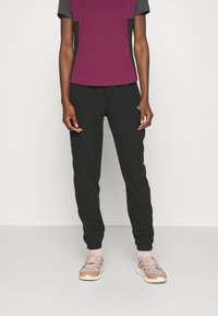 Sportig outfit bestående av en lila och grå kortärmad t-shirt, svarta byxor och ljusa sneakers med rosa detaljer och gråa inslag.