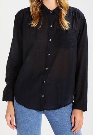 Black, sheer button-up shirt with a collar, single chest pocket, and long sleeves. Light, flowing fabric with a relaxed fit and rounded hem.