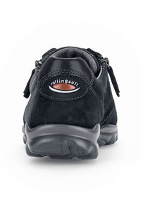 Zwarte suedine sneaker met een ronde vorm, gevoerde zool en ritsluiting. Heeft discrete branding in het rood op de hak en textuuraccenten.