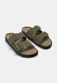 Olivengrøn nubuck sandaler med to justerbare sølvspænder, flade sorte gummisulder og lysebrune indersåler. Casual slide design.