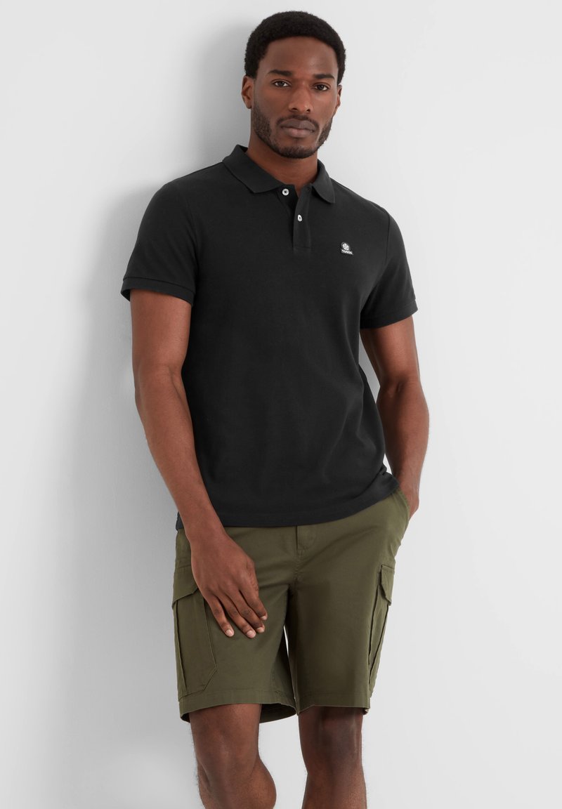 Black polo shirt with short sleeves, featuring a logo on the left chest, paired with olive green cargo shorts with side pockets.