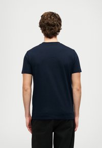 Navy zils kokvilnas T-krekls arapaļo izgriezumu, īsām piedurknēm un gludu tekstūru. Iezīmē vienkāršu, nenozīmētu dizainu.