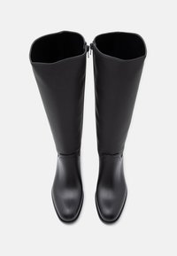 Črne škornje do kolen, izdelane iz gladkega materiala, z ravnim podplatom, kvadratnim nosom in zadrgo na hrbtni strani za enostavno obuvanje.