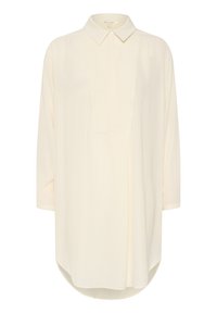 Vaaleancremoinen pitkähiha shirtti, jossa on klassinen kaulus, teksturoitu ruutukuvio ja hieman kaareva helma. Sisältää etunapitusosaston.