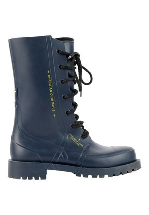 Botte de combat en caoutchouc bleu marine avec lacets noirs, semelle épaisse et texte "Christian Dior Paris" en jaune sur le côté.