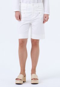 Witte katoenen shorts met een rechte snit, opgerolde zoom, voor- en achterzakken, gecombineerd met gestructureerde platformsandalen.