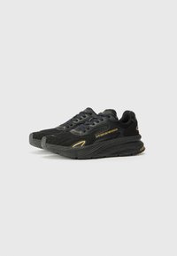 Black athletic shoes with a textured mesh and synthetic upper, featuring gold branding, a cushioned sole, and a layered design.