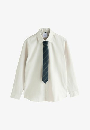 Herren-Hellbeiges Hemd mit Spitzkragen, kombiniert mit hellbraunen, strukturierten Hosen und einer marineblauen Krawatte mit diagonalen Streifen.