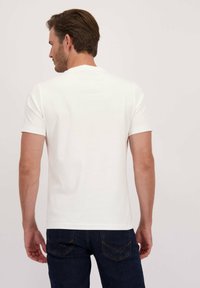 Witte t-shirt met korte mouwen, van achteren bekeken, gemaakt van zachte stof, met een ronde hals en een eenvoudige uitstraling. Gecombineerd met donkerdenim jeans.