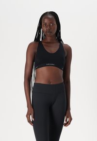 Black sports bra with a v-neck design and a wide band featuring "icebreaker" branding. Slim-fit leggings in matching black. Smooth texture.