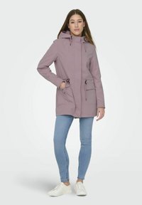 Helllilac Parka-Jacke mit Kapuze, Reißverschluss auf der Vorderseite, Kordelzug in der Taille und zwei Seitentaschen. Getragen über blauen Skinny-Jeans und weißen Sneakers.
