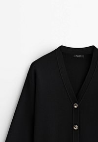 Czarny kardigan z dekoltem w serek, z prążkowanymi brzegami i dwoma metalowymi guzikami. Wykonany z gładkiego, miękkiego materiału. Minimalistyczny design.