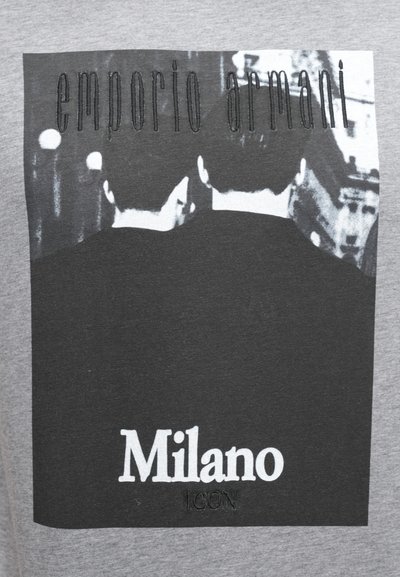 Γκρι μπλουζάκι με μαύρο και λευκό γραφικό δύο φιγούρων από πίσω. Το κείμενο γράφει «emporio armani» και «Milano ICON» σε αντιθετικά χρώματα.