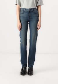 Blå denimjeans med slim straight fit, med fem lommer, beltefelter og subtil falming, brukt med svarte platå sko.