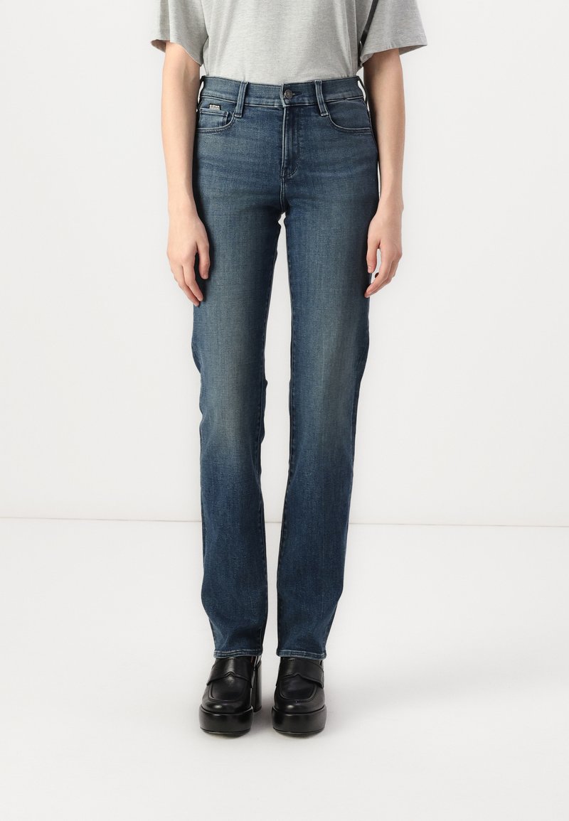 Blå denimjeans med slim straight fit, med fem lommer, beltefelter og subtil falming, brukt med svarte platå sko.