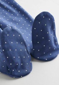 Blå strumpor med vita prickar; mjukt tyg. Har rundade tåsektioner och en slät yta. Betonar kanter för en färdig look.