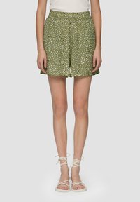 Zielone spodenki w wzory z elastycznym paskiem w talii, zdobione białymi kropkami. W połączeniu z białymi sandałami na sznurówki.