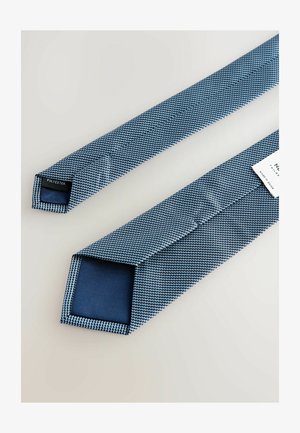 Blauer Polyester-Krawatte mit texturiertem Muster und einfarbigem blauen Rückenteil, mit einer spitzen Kante und einem beschrifteten Etikett am schmalen Ende.