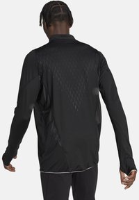 Giacca sportiva nera a maniche lunghe con parte superiore strutturata, pannelli in rete sotto le braccia e design slim fit.
