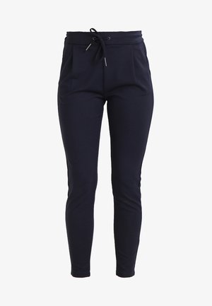 Marineblå joggebukser i stretch med snøring i midjen, tapered ben-design og frontfoldinger for ekstra detaljer. Myk tekstur.