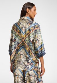 Hieno kimono-tyylinen paita kevyestä kankaasta, jossa on monivärinen kukkakuvio ja geometrinen kuvio, rento istuvuus ja hihansuut.
