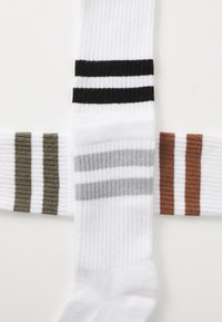 White socks with ribbed texture; features black, olive green, grey, and orange stripes. Each sock displays contrasting horizontal stripes.