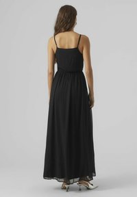 Robe maxi en tissu noir, avec un corsage ajusté doté de fines bretelles et d'une taille élastique, jupe fluide ; texture lisse et longueur cheville.