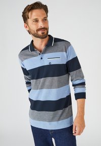 Polo a maniche lunghe con righe alternate in azzurro chiaro, blu navy e grigio. Con colletto, patta con bottoni e taschino sul petto.