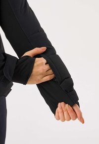 Manica di giacca imbottita nera con tessuto liscio a trama trapuntata, apertura per il pollice e polsino regolabile con Velcro.