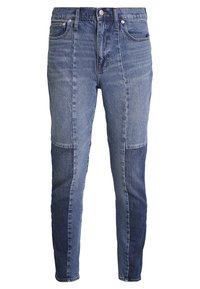 Vaqueros de mezclilla con un diseño bicolor que combina parches en tonos azul claro y oscuro, un corte ajustado, cinco bolsillos y cierre con botón en la cintura.