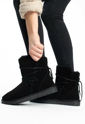 Black ankle boots made of soft suede, featuring laces, a textured exterior, and a sturdy rubber sole with a slightly raised heel.