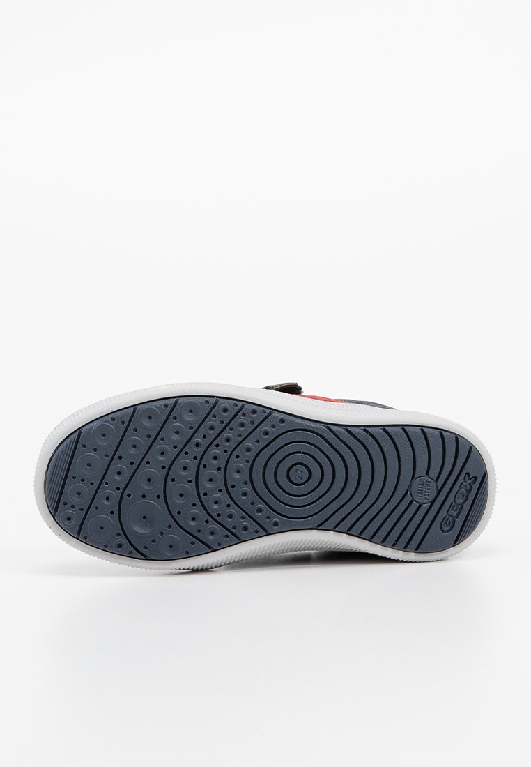 Semelle de sneaker bleu et blanc avec des motifs de traction circulaires et des trous de drainage ; présente un marquage et une construction en caoutchouc texturé.