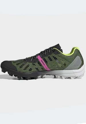 Black and green athletic shoes with a mesh upper, textured accents, and a pink logo. Designed with a rugged outsole for traction.