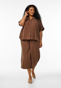 Brown textured co-ord set featuring a short-sleeve, button-front top and wide-leg pants, complemented by woven beige shoes.