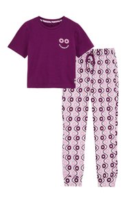 Camiseta de algodón morada con gráfico de una flor sonriente, combinada con pantalones blancos que presentan un patrón floral morado y una cinturilla elástica.