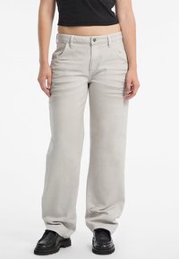 Jeans a gamba larga grigio chiaro in denim, con chiusura anteriore a bottoni, due tasche frontali e una texture leggermente sbiadita. Scarpe nere in vista.