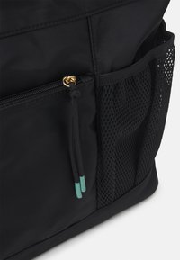 Bolsa de tela negra con un compartimento con cremallera y herrajes dorados, además de un bolsillo lateral de malla. Incluye un borlas decorativas con acentos en teal.