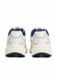 Scarpe da ginnastica bianche con accenti blu navy, costruzione in rete, colli imbottiti e suole testurizzate. Design minimalista con dettagli sottili.