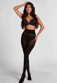 Schwarze, hoch taillierte Strumpfhosen mit transparenten Einsätzen, die die Beine betonen; kombiniert mit einem schwarzen BH. Glatte Textur, figurbetontes Design. Keine Muster oder Verzierungen.