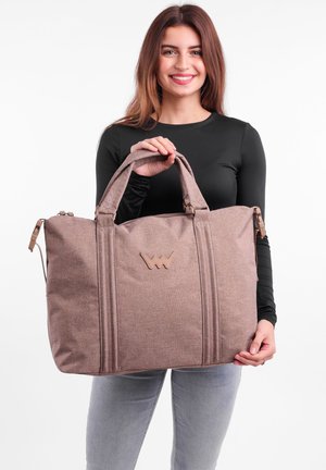 Braune Stofftasche mit zwei Griffen, Reißverschluss und strukturiertem Design. Verfügt über ein geprägtes Logo und vertikale Nähte zur Formgebung.