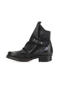 Botín de cuero negro hasta el tobillo con parte superior plegada, detalle de correa y un tacón bajo apilado. Textura suave con un brillo sutil.