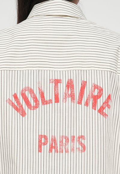 Röstripeeritud särk, mille seljal on punane, kulunud "VOLTAIRE PARIS" trükk, valge kangas kitsaste pruunide triipudega.