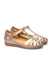 Tan en metallic gouden dames sandalen met kruisbanden, open teen, gevlochten stiksel en een platte rubberen zool.