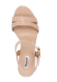 Sandale à talons hauts en vernis beige avec deux larges brides sur le devant et une bride à la cheville avec des accessoires dorés. Fini lisse et brillant.