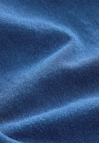 Tissu bleu avec une texture lisse et légèrement brillante, présentant un tissage fin et un éclat subtil, formé en plis doux et fluides.