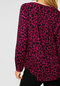 Blusa a maniche lunghe in stampa leopardata rosa e nera, con una vestibilità morbida e dettaglio plissettato sul retro. Tessuto morbido con una texture liscia.