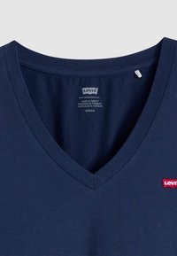 Sötétkék pamut V-nyakú póló, mely a mellkasán egy kis piros Levi's logót visel, sima textúrával és szabványos fazonnal.